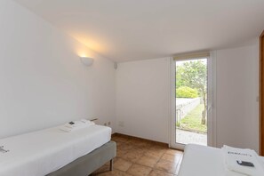 Ein Schlafzimmer mit einem Bett, einem Nachttisch, einer Wandleuchte und einer Glastür, die zu einem Außenbereich führt.