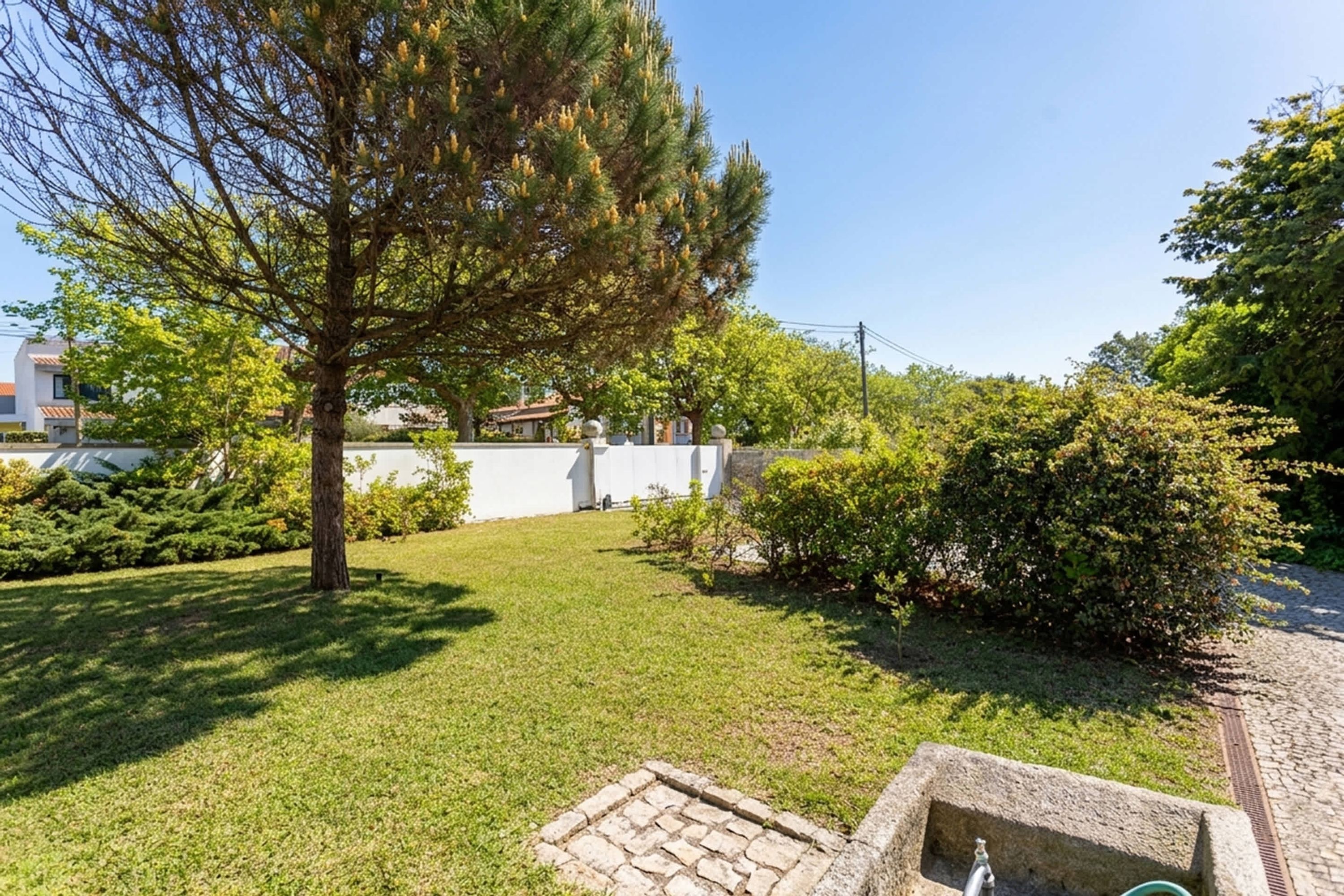 Un jardin bien entretenu, avec une pelouse, un grand arbre et une construction en pierre.