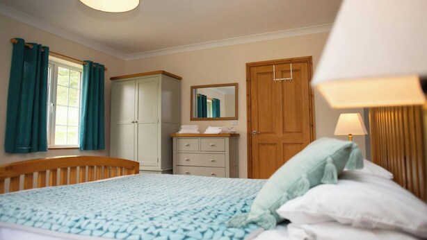 Quarto com cama, guarda-roupa, penteadeira e espelho.