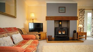 A cozy living room with a sofa, a television, a fireplace, and a lamp.