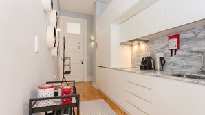 A modern kitchen with white cabinets, a marble backsplash, a coffee maker, and a kettle. - Liiiving in Porto - Blue Stylish Studio (Porto)