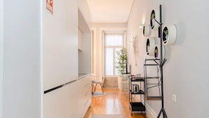 A modern kitchen with white cabinets, a wooden floor, and a dining area with a table and chairs. - Liiiving in Porto - Blue Stylish Studio (Porto)