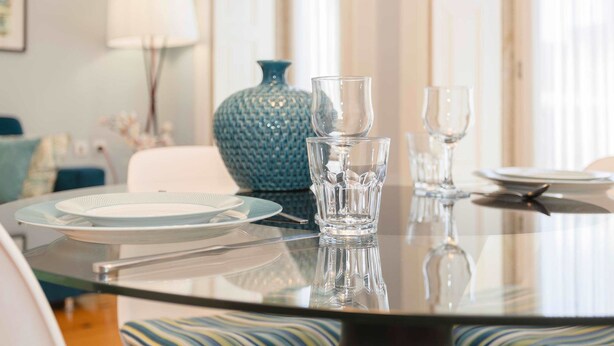 A dining table with plates, glasses, and cutlery, set in a room with a lamp and a vase. - Liiiving in Porto - Blue Stylish Studio (Porto)