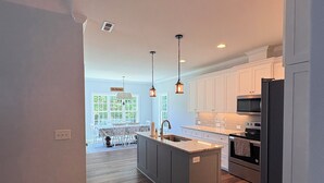 A modern kitchen with a central island, stainless steel appliances, and pendant lighting. - Secluded Harris Lake retreat. Nature, privacy, and Lake access to a private cove (New Hill)