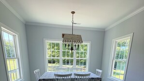 A dining room with a table and chairs, large windows, and a chandelier. - Secluded Harris Lake retreat. Nature, privacy, and Lake access to a private cove (New Hill)