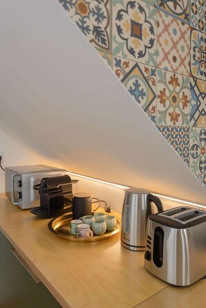 Eine Küchenarbeitsplatte mit Toaster, Kaffeemaschine, Wasserkocher und einer Schale mit Tassen.