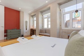 Ein Schlafzimmer mit einem Bett, einem Schminktisch, einem Spiegel und einem Fenster mit Blick.