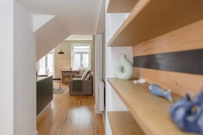 Un intérieur moderne avec un plancher en bois, un coin repas comprenant une table et des chaises, et un espace cuisine avec des placards et un radiateur.