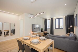 Una sala de estar moderna con comedor, sofá gris, televisor de pantalla plana y un letrero que dice 'Living'.