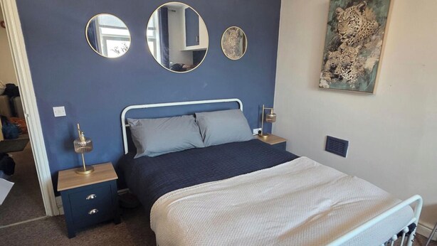 A bedroom with a bed, two bedside tables, a mirror, and a painting on the wall. - 1 Bedroom Beach View Apartment Sleeps 4 (Rhyl)