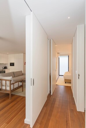 Eine moderne Wohnung mit Holzboden, einer Couch, einem Bett und einer Küchenzeile.