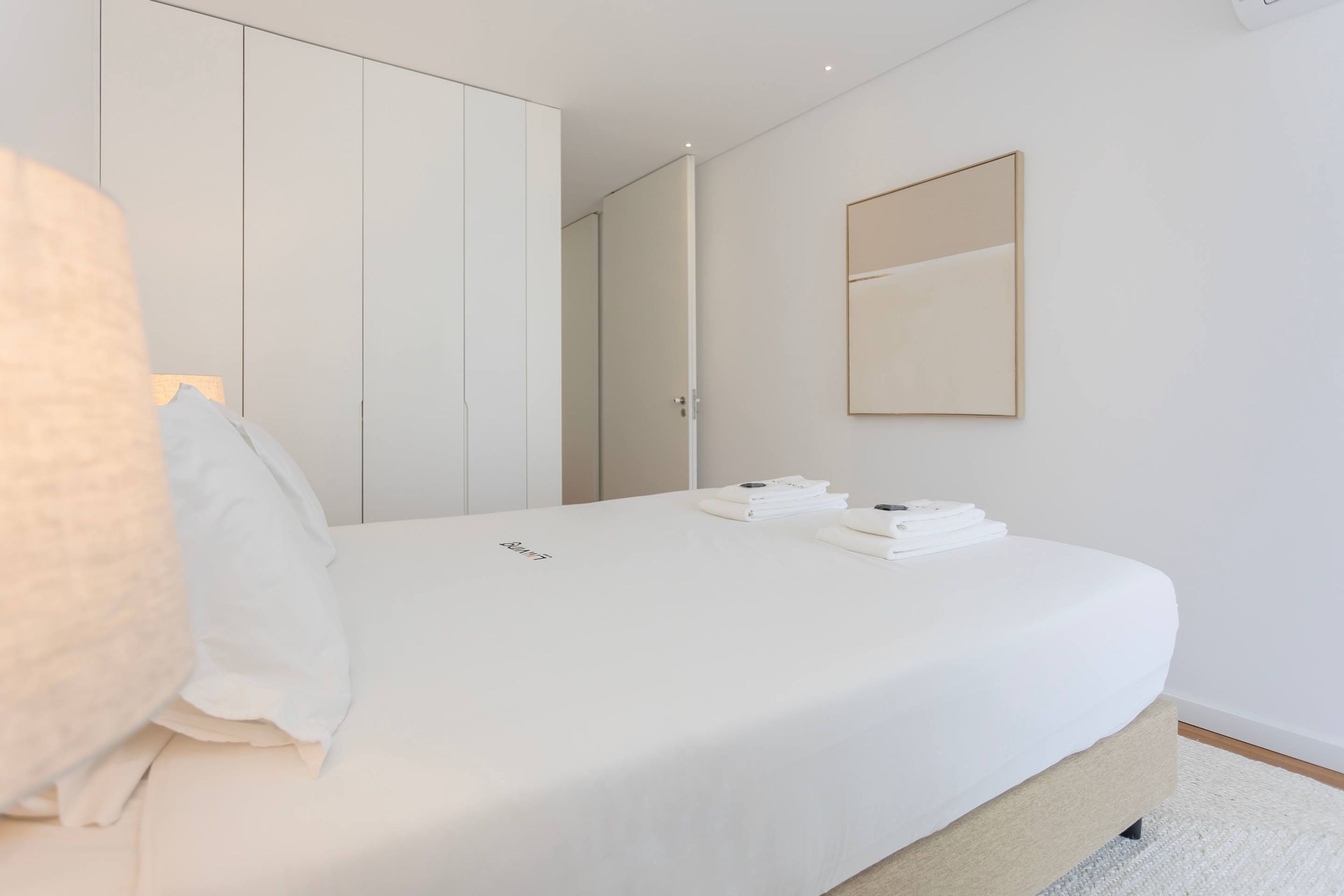 Une chambre à coucher comprenant un lit, une armoire, un miroir et une petite table avec des serviettes.
