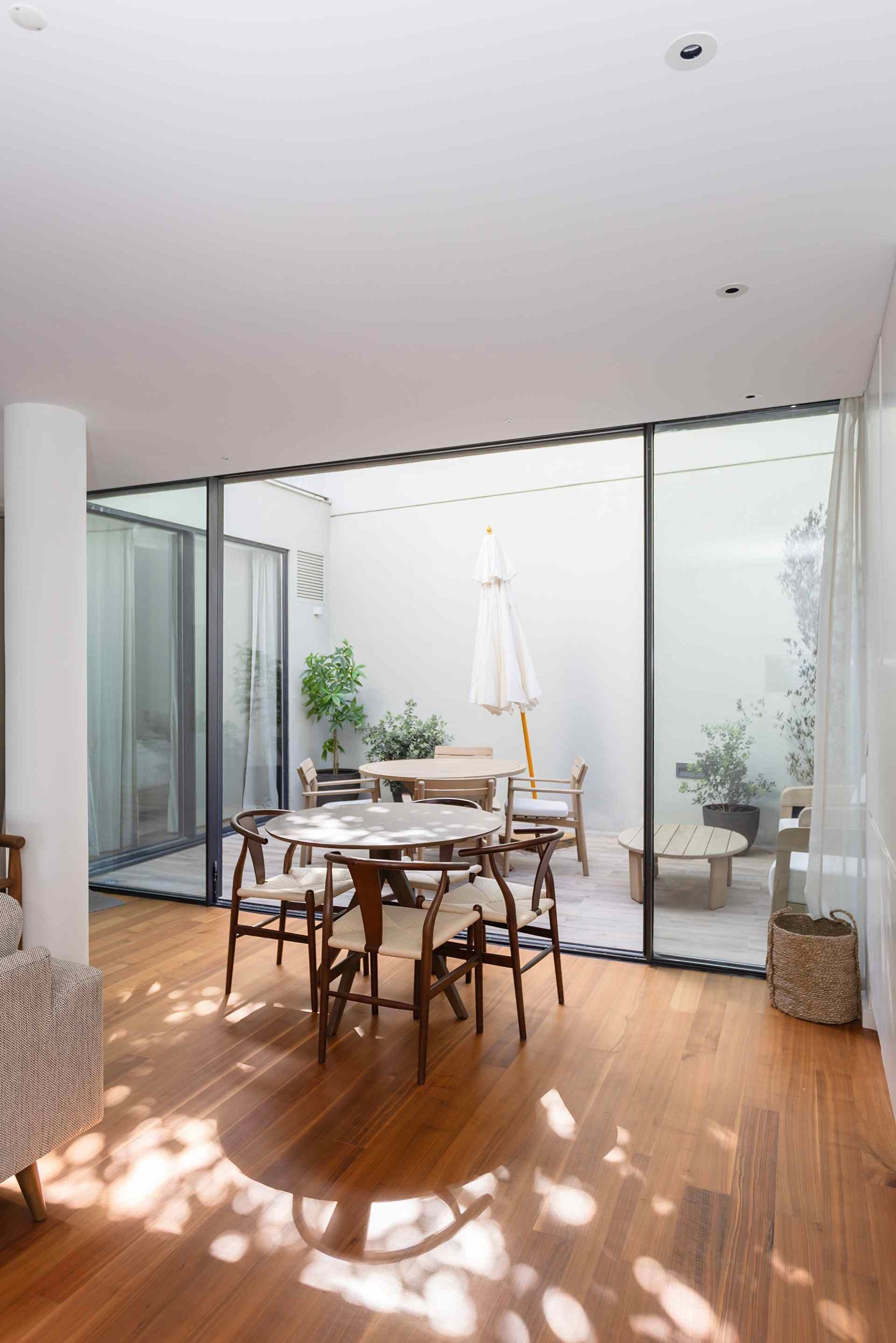 Un intérieur moderne comprenant un coin repas, de grandes portes vitrées et une vue sur l’extérieur.