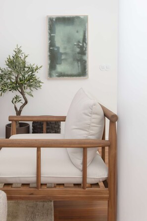 A wooden sofa with a cushion and a pillow, a bonsai tree, and a painting on the wall. - Liiiving in Porto - The Prestige Apartment F (Porto)