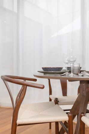 A dining area with a round table, chairs, and a window with sheer curtains. - Liiiving in Porto - The Prestige Apartment F (Porto)