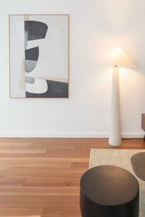 A room with a modern floor lamp, a round black ottoman, and a piece of abstract art on the wall. - Liiiving in Porto - The Prestige Apartment F (Porto)