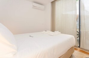 A hotel room with a bed, a window with curtains, and an air conditioning unit on the wall. - Liiiving in Porto - The Prestige Apartment F (Porto)