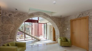 Amplia sala de estar con un arco de piedra que da a un balcón, una puerta de madera y una escalera.