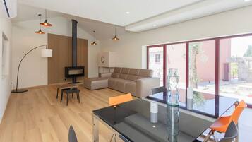 Una sala moderna con sofá, una mesa de comedor de vidrio y una chimenea.