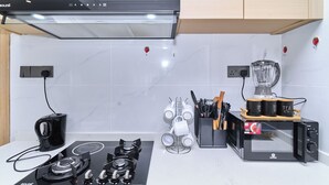 Uma cozinha com fogão a gás, cafeteira, liquidificador e suporte para canecas.