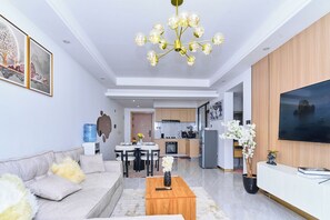 A modern living room with a sofa, coffee table, chandelier, dining area, kitchen, and TV. - Leshwa House 1 is situated in the high end of Nairobi with tranquil and Ambience (Nairobi)