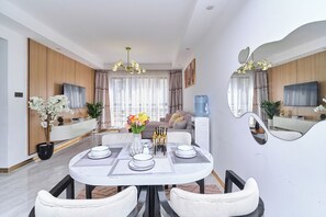 A modern dining area with a round table, white chairs, and a vase of flowers. - Leshwa House 1 is situated in the high end of Nairobi with tranquil and Ambience (Nairobi)