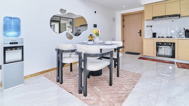Uma cozinha moderna com forno embutido, dispensador de água e espaço de refeições com mesa redonda e cadeiras.