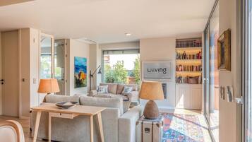 A modern living room with a sofa set, a table with a bowl, lamps, a rug, and a bookshelf.