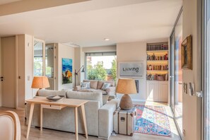 A modern living room with a sofa set, a table with a bowl, lamps, a rug, and a bookshelf. - Liiiving in Porto - Foz Garden House (Porto)