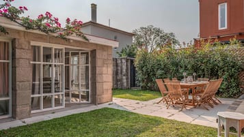 A patio with a table and chairs, a grassy lawn, and a building with a stone facade.