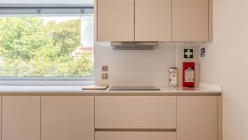 A kitchen with cabinets, a window, a fire extinguisher, and a first aid kit.