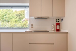 A kitchen with cabinets, a window, a fire extinguisher, and a first aid kit. - Liiiving in Porto - Foz Garden House (Porto)