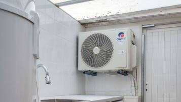 A compact laundry room with a washing machine, a dryer, and a ceiling-mounted air conditioning unit.