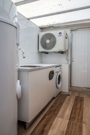 A compact laundry room with a washing machine, a dryer, and a ceiling-mounted air conditioning unit. - Liiiving in Porto - Foz Garden House (Porto)