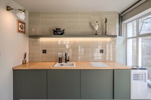 A kitchen with a modern design, featuring a light-colored tile backsplash, a wooden countertop, and a built-in sink. - Liiiving in Porto - Foz Garden House (Porto)