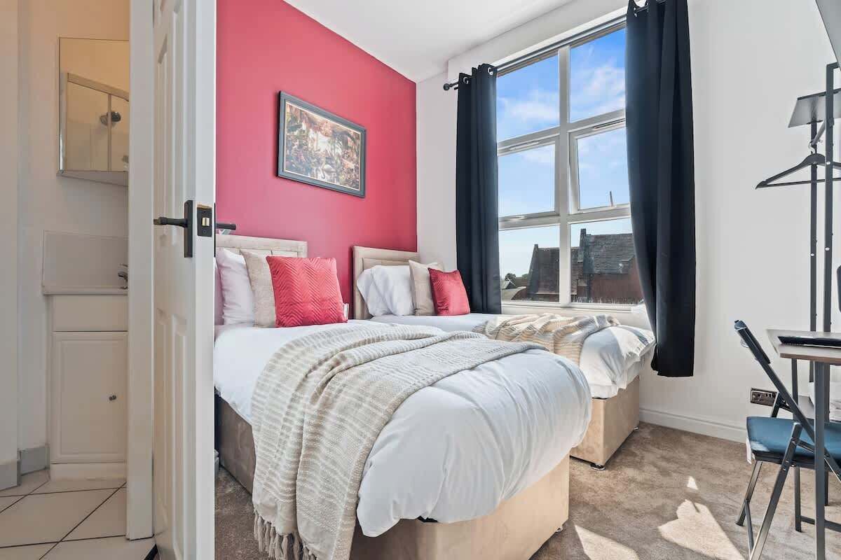 A bedroom with a bed, a desk, and a window.