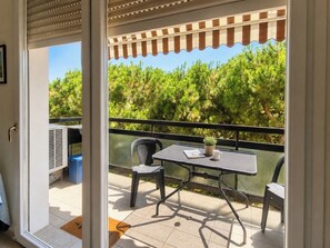 A balcony with a table, chairs, a potted plant, and a view of trees. - Casa delle anatre By Case al Lago (Desenzano del Garda)