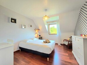Quarto com cama, mesa de cabeceira, abajur, cômoda e janela com vista.