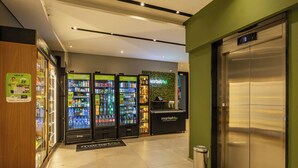 A modern lobby with vending machines, a reception desk, and an elevator. - StayHome Moema NexOne Pool & Gym (São Paulo)