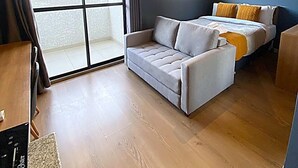A bedroom with a bed, a sofa, a window, and a ceiling fan. - StayHome Moema NexOne Pool & Gym (São Paulo)