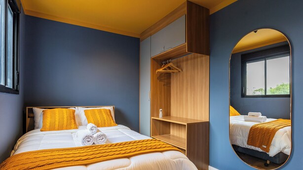 A hotel room with a bed, a mirror, a wardrobe, and a window. - StayHome Moema NexOne Pool & Gym (São Paulo)