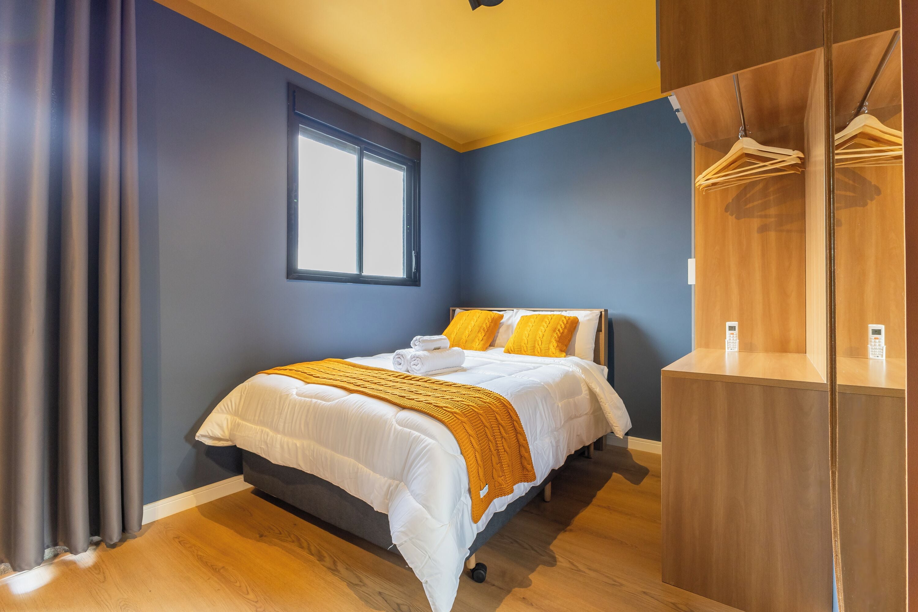 A bedroom with a bed, a window, a wardrobe, and a bedside table.