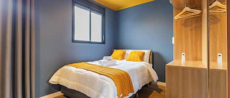 A bedroom with a bed, a window, a wardrobe, and a bedside table.