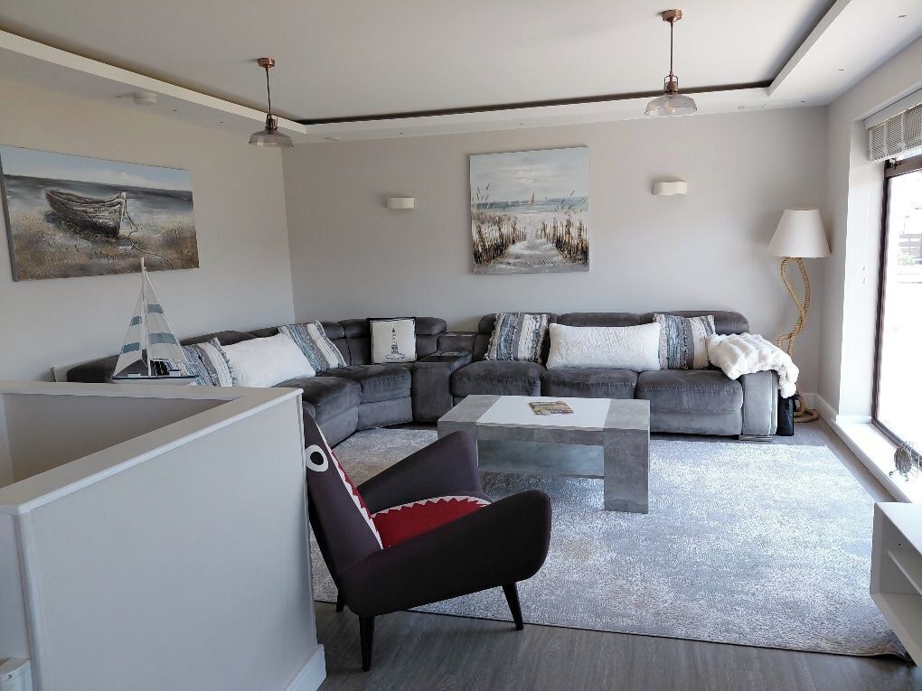 A modern living room with a sectional sofa, a coffee table, and artwork on the walls.