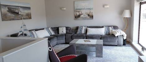 A modern living room with a sectional sofa, a coffee table, and artwork on the walls.
