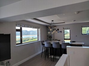 A modern kitchen with a dining area, large windows with a view, and a chandelier. - Lovely Beach House In Deganwy | Conwy | Sleeps 6 (Deganwy)