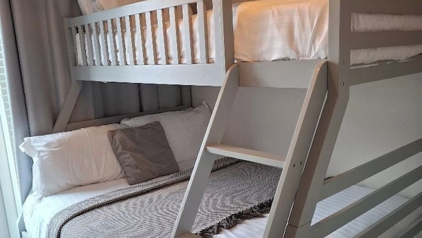 Ein Stockbett mit einer Leiter, weißer Bettwäsche und einem Bild an der Wand.