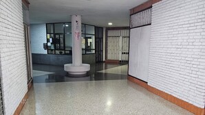 Un corridoio con pareti in mattoni bianchi, una colonna centrale e un pavimento piastrellato.