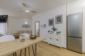 A modern kitchen with a wooden dining table, white cabinets, a stainless steel refrigerator, and a ceiling fan. - Solajero Apartment in Las Canteras (Las Palmas de Gran Canaria)
