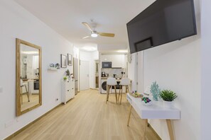 Et moderne køkken med hvide skabe, en mikrobølgeovn og en kaffemaskine.